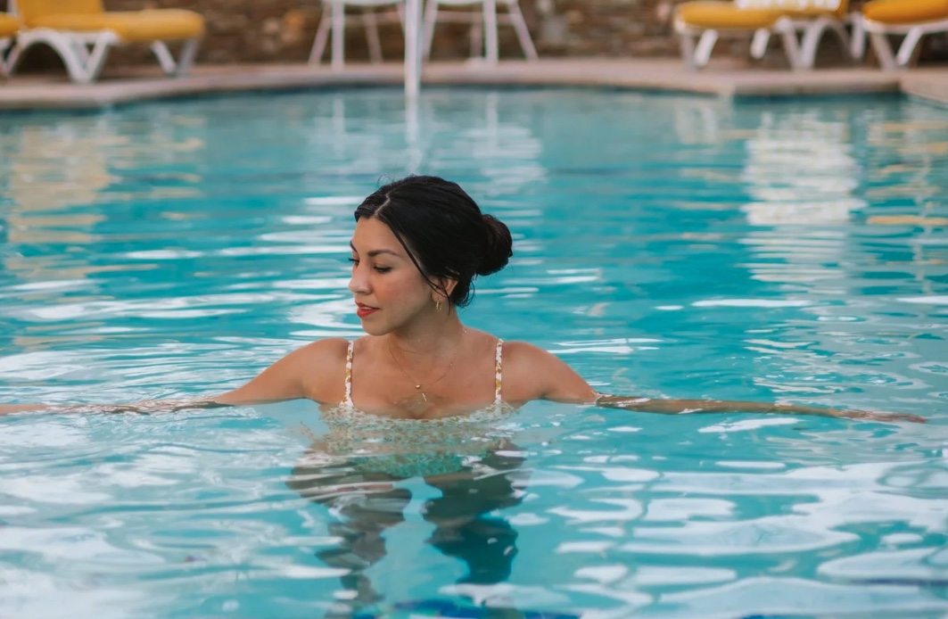 Woman soaking in mineral pool surrounded by yellow lounge chairs