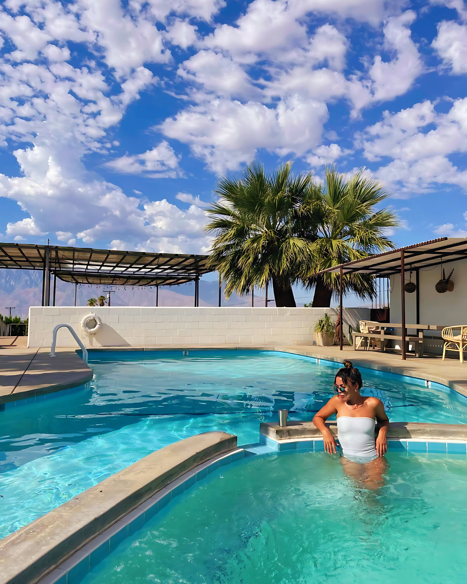 Woman relaxing in a mineral pool with palm tree and San Jacinto mountain views — healing waters of Desert Hot Springs