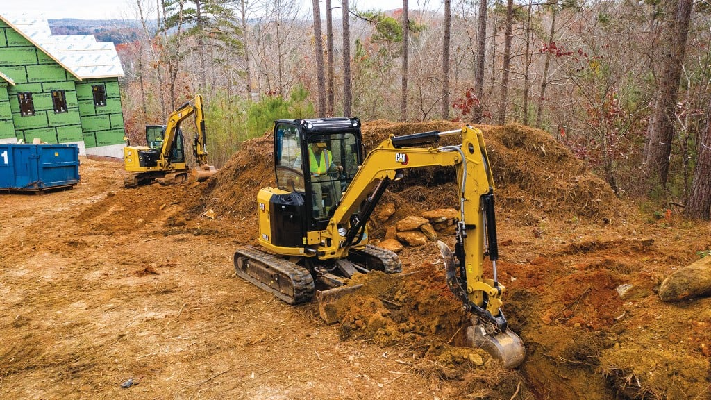 Two yellow excavators working on large construction site clearing