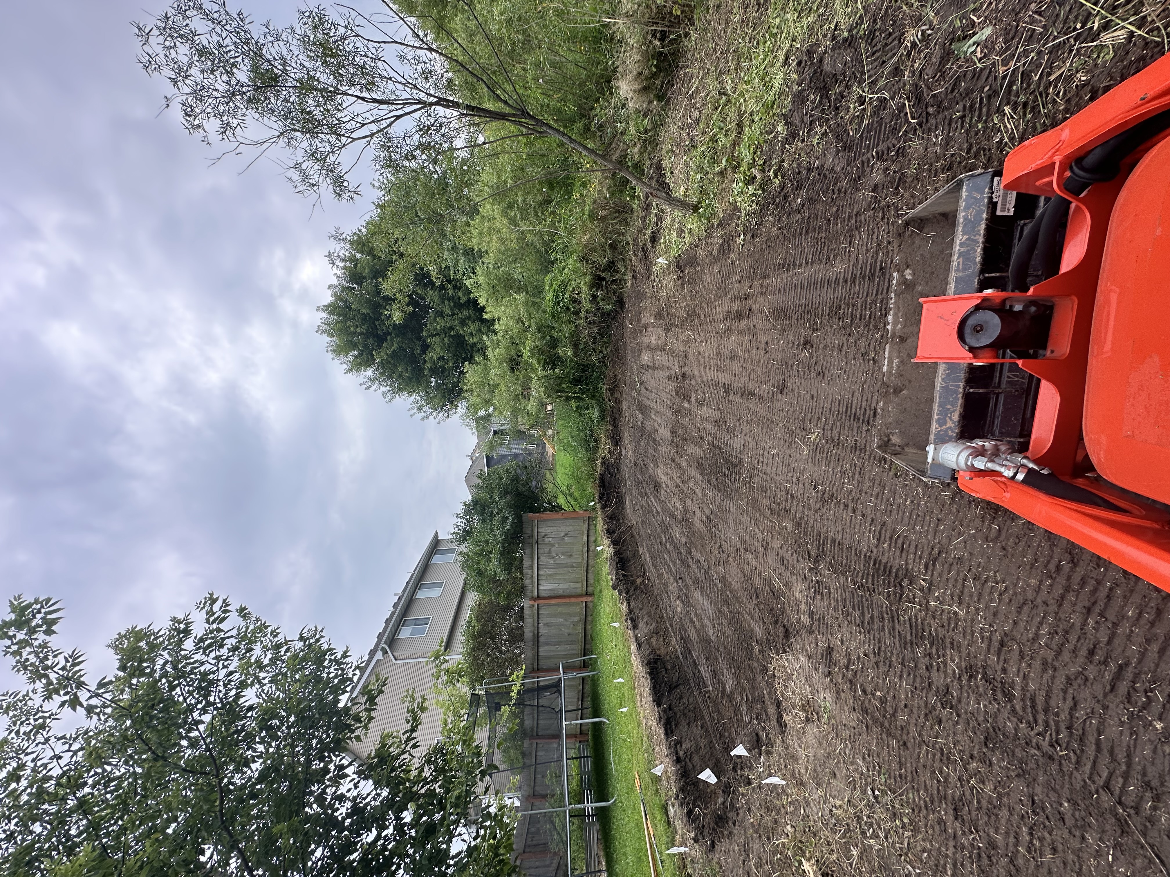 Red skid steer on newly prepared site with house in background