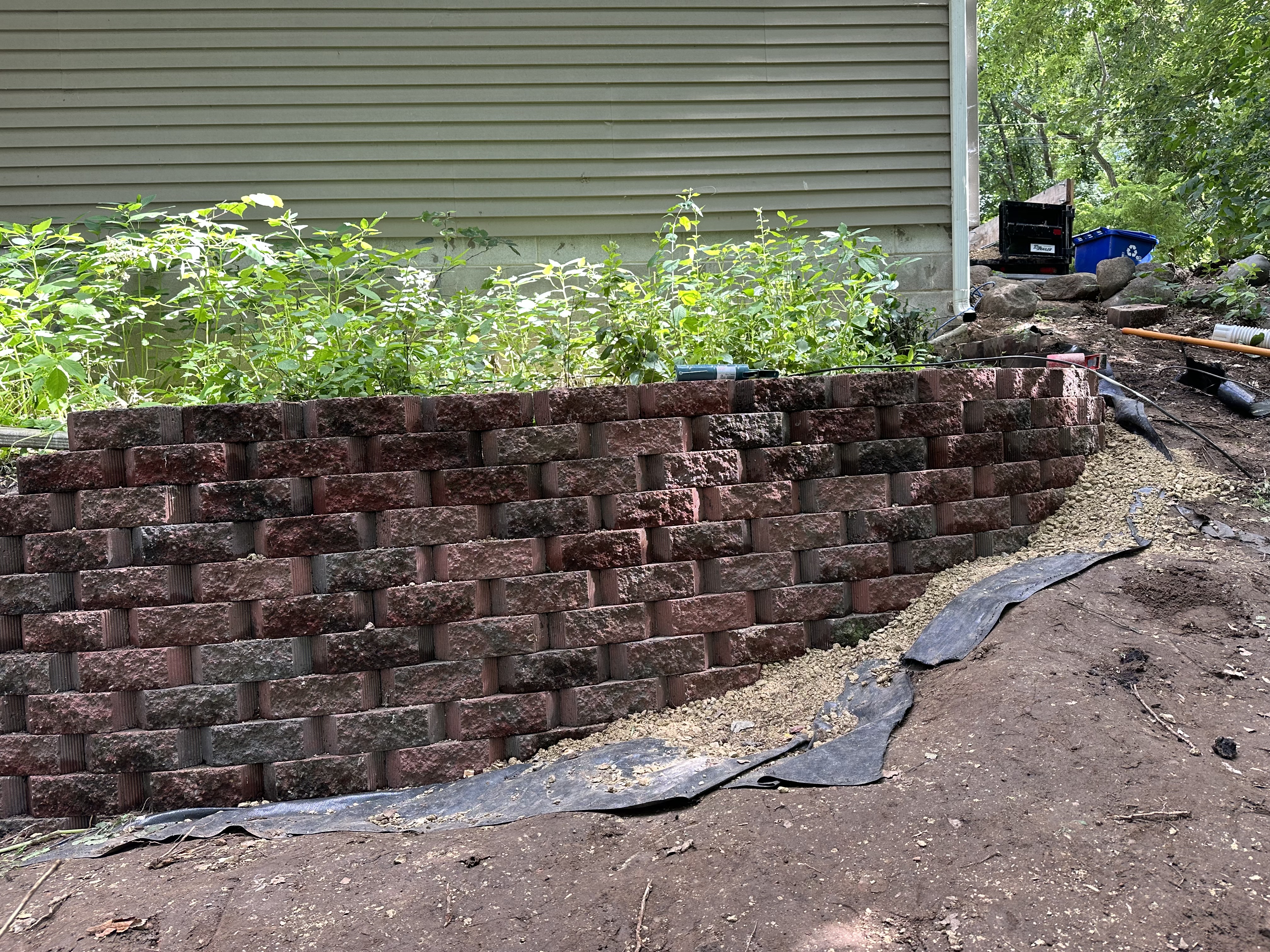 Professional retaining wall construction showing proper foundation and drainage installation with quality materials