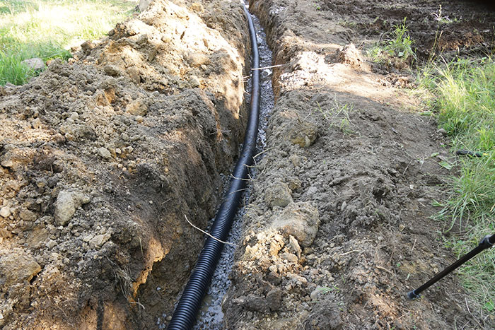 Black corrugated drainage pipe laid in excavated trench