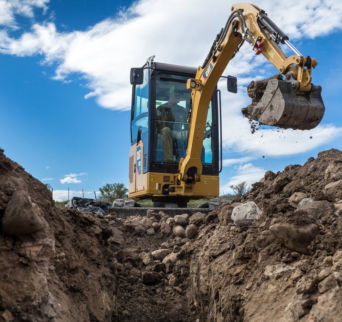 Mini excavator performing precision excavation work from elevated position