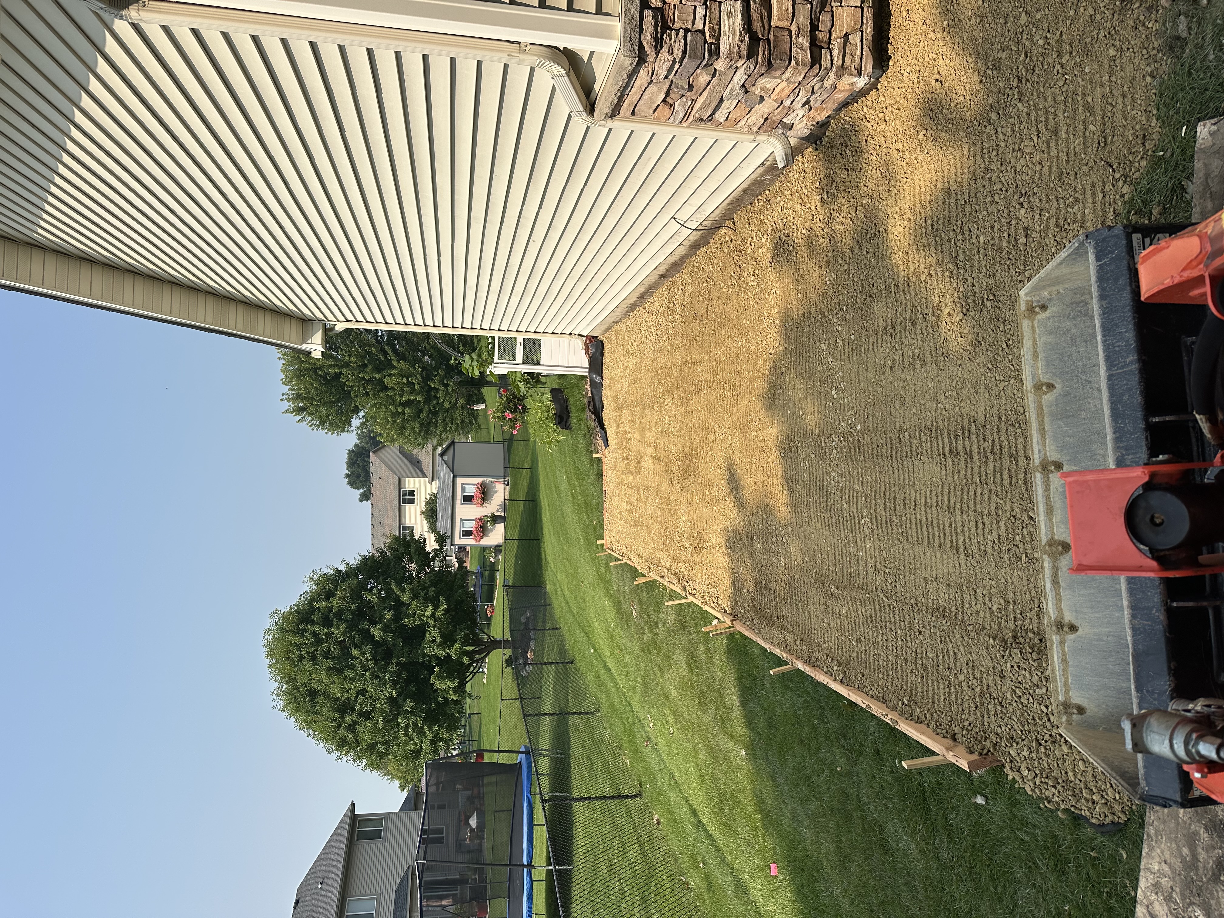 Freshly graded residential yard with compact tractor visible