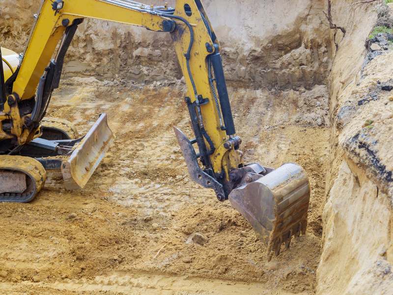 Close-up of excavator bucket working in sandy soil excavation